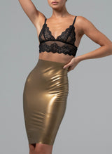 Woman wearing a black lace bralette and gold metallic latex skirt on a grey background