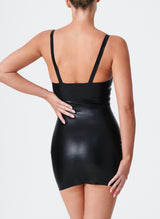 Back shot of a person wearing a black latex mini dress with narrow shoulder straps and gold buckles.