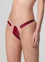 A model wearing a plum latex rubber thong with baby pink latex inserts.
