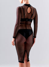 Back view of a model wearing a black fishnet pencil dress with high collar and long sleeves, over black latex lingerie, on a grey background.