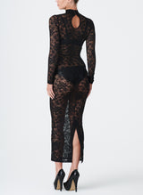 A model wearing a long black lace dress with a high collar and fitted sleeves. The dress features a keyhole at the back neck and a split at the back hem.