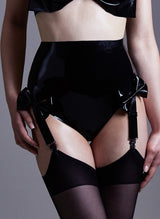 High waisted black latex knickers with four adjustable suspender straps attached and bows at the front, worn with black stockings.