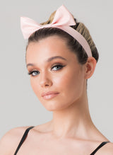 A person wearing a baby pink latex mini hair bow with a pleated design, set against a neutral background.
