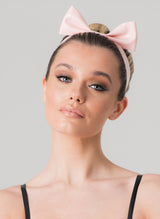 A person wearing a baby pink latex mini hair bow with a pleated design, set against a neutral background.