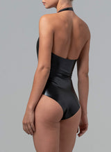 Back view of a model wearing black latex rubber halter neck bodysuit.