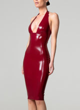 A model wearing a plum coloured latex pencil dress with a plunging halter neck.