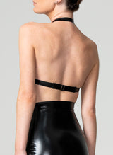 Back shot of a model wearing a black latex bikini style bra with a halter neck by William Wilde. Black latex girdle also in shot.