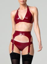 A model wearing a plum latex rubber lingerie set, including halter neck bikini-style bra, four strap suspender belt and hipster briefs. Black stockings also shown, all by designer William Wilde.