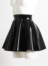 A black latex circle skirt with fitted waistband, on a mannequin.