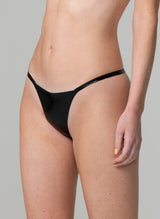 A person wearing a black latex G-string that features narrow latex straps. The image shows the person from the waist down, focusing on the garment.