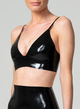 A model wearing a black latex bra with a V neckline and adjustable shoulder straps. Matching latex suspender belt also in shot, all by designer William Wilde.