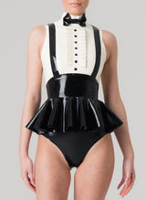 A model wears a sleeveless latex blouse with a flared peplum and mock shirt front, featuring a bow tie and braces. The blouse is primarily black with white upper section. Worn with matching black latex knickers.