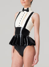 A person wearing a sleeveless latex blouse with a flared peplum and mock shirt front, featuring a bow tie and braces. The blouse is primarily black with white upper section. Worn with matching black latex knickers.
