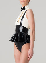 A sleeveless latex blouse with a flared peplum and mock shirt front, featuring a bow tie and braces. The blouse is primarily black with white upper section. Worn with matching black latex knickers.