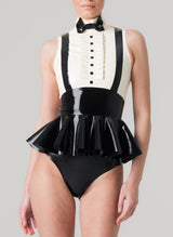 A sleeveless latex blouse with a flared peplum and mock shirt front, featuring a bow tie and braces. The blouse is primarily black with white upper section. Worn with matching black latex knickers.