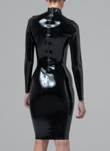 Back view of a person wearing a black latex knee-length dress, with a high collar and long sleeves, standing against a grey background.