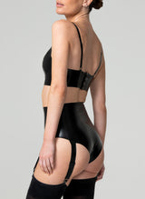 Back view of a person wearing a black latex lingerie set, including a longline triangle bra with adjustable shoulder straps and a high waisted suspender knickers with four adjustable suspender straps. Worn here with black stockings.