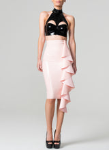 A black latex bra top by William Wilde with a high collar and keyhole cut-outs, worn by a model wearing a pale pink latex skirt against a neutral background.