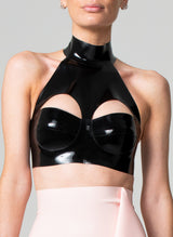 A black latex bra top by William Wilde with a high collar and keyhole cut-outs, worn by a model against a neutral background.
