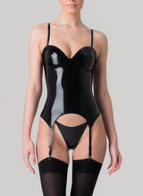 A person wearing a black latex basque with adjustable shoulder straps and suspender straps, featuring a zip fastening at the back, presented against a grey background, and worn with a matching G-string and black stockings.