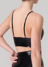 Back shot of a model wearing a black latex bra with gold front zip and studs, paired with matching black latex knickers.