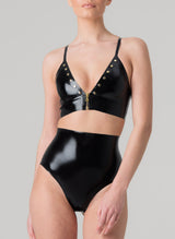 A model wearing a black latex lingerie set with longline triangle bra and high waisted knickers, featuring adjustable shoulder straps, gold front zip and stud detailing at bust.