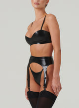 A model wearing a black latex rubber lingerie set, including bra, suspender belt and g-string. Black stockings also worn.