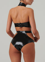 Back view of a black latex bra top by William Wilde with a high collar and keyhole cut-outs, worn by a model wearing black latex knickers with hip cut-outs, against a neutral background.