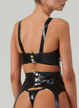 Back shot of a black latex bra with gold fastenings.