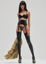 A black latex lingerie set with gold suspender clasps and rings, featuring adjustable straps. The set includes a bra, suspender belt and G-String. The model wears black latex stockings and a gold tinsel coat.