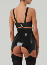 A person from behind wearing a black latex girdle with matching gold suspender clips. Also wearing black latex bra and opaque stockings.