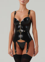 A person wearing a black latex basque with gold hardware and front zip, along with matching adjustable belt and suspender straps.