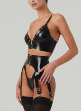 Side view of a person wearing a black latex lingerie set and black stockings. The set includes gold studded bra and suspender belt, both with gold front zips, and matching latex thong.
