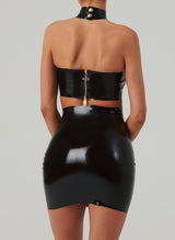 Back shot of a person wearing a black latex mini dress with gold zip at back.