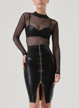 A person wears a high waisted black latex pencil skirt with a gold front zip, paired with a latex bra and black fishnet top.