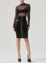 A model wears a high waisted black latex pencil skirt with a gold front zip, paired with a latex bra and black fishnet top.