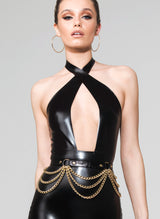 Model wearing a black latex dress with crossover neckline, and a black leather belt with gold rings and chains.
