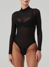 A black sheer bodysuit with long sleeves and a high neck. Worn over black latex lingerie.