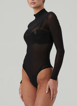 A black sheer bodysuit with long sleeves and a high neck. Worn over black latex lingerie.