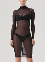 A woman wearing a black mesh dress with long sleeves, a high neck, and a keyhole back, paired with black latex lingerie visible underneath.