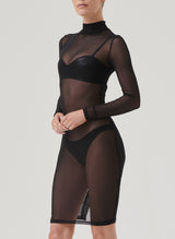 A model wearing a black mesh pencil dress with long sleeves, a high neck, and a keyhole at back, paired with black latex lingerie, visible underneath.
