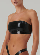 A person wearing a black latex bandeau top with press studs at the back, matching with a latex high leg thong, both items are designed for women, by William Wilde.