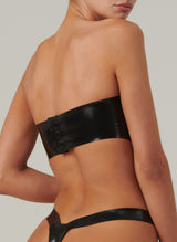 Back shot of a person wearing a black latex bandeau top with press studs at the back, shot with matching latex high leg thong, both items are designed for women, by William Wilde.