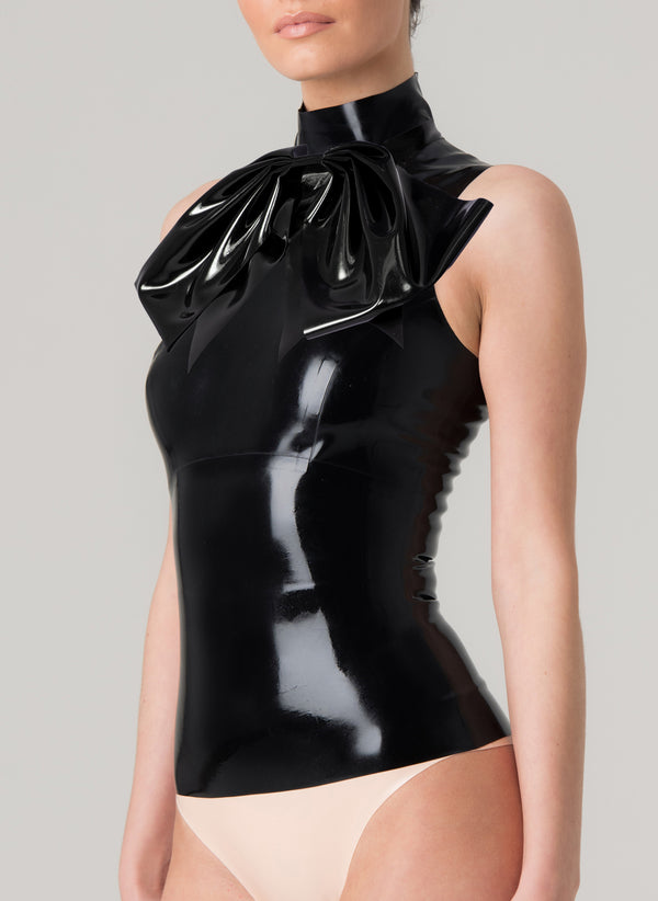 A black latex sleeveless top with XL pussy bow at neck, worn by a model on a gray background.
